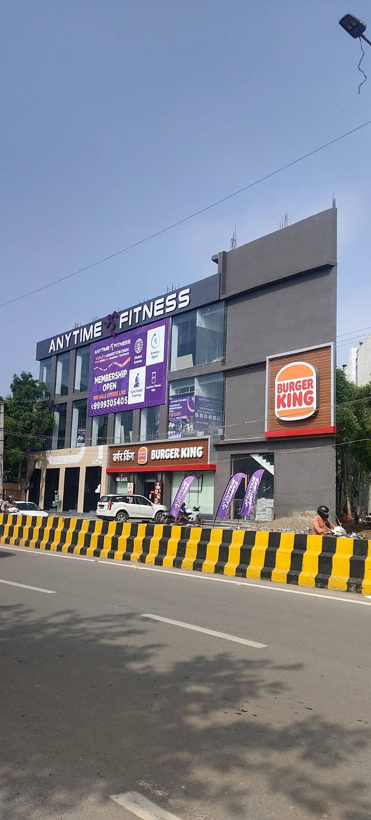 Glass facade and shopfronts of the Anytime Fitness and Burger King complex, Gurugram